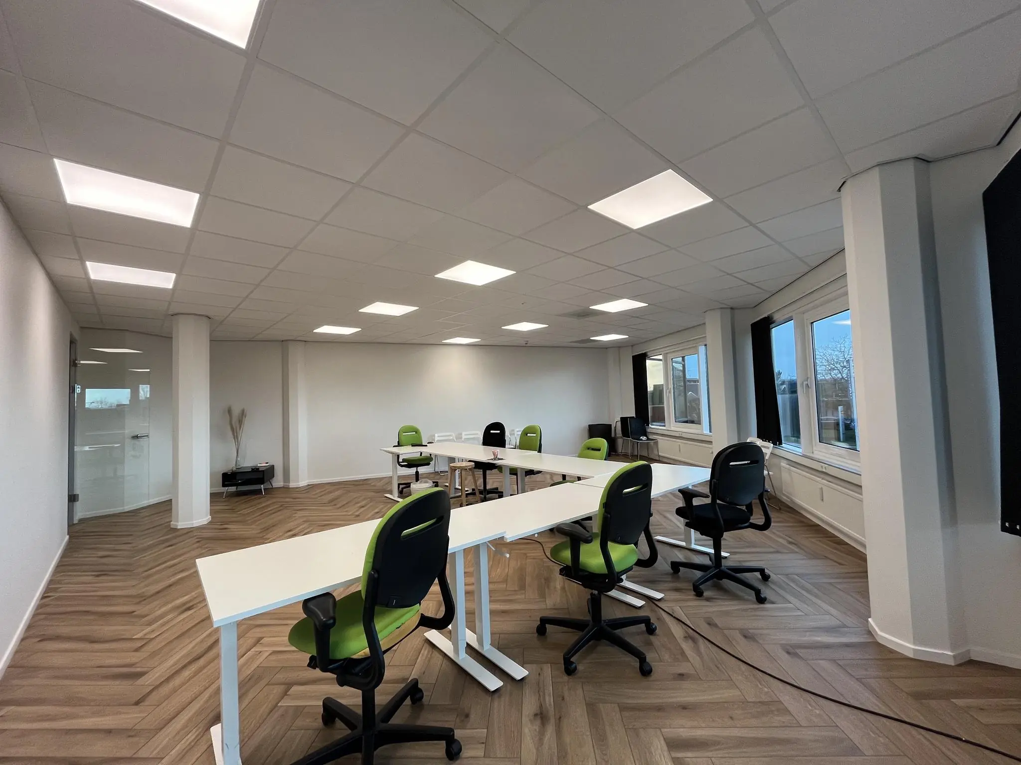 Moderne vergaderruimte aan de Lange Dreef met flexibele bureaus en groene bureaustoelen.